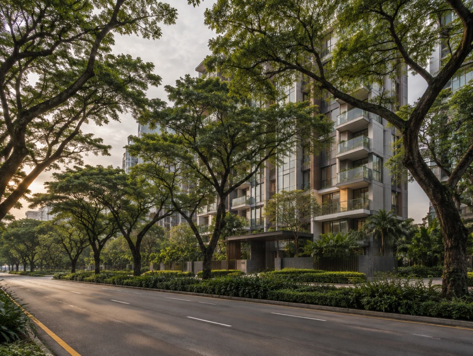 Tree-lined boulevard with a condominium facade behind rain trees